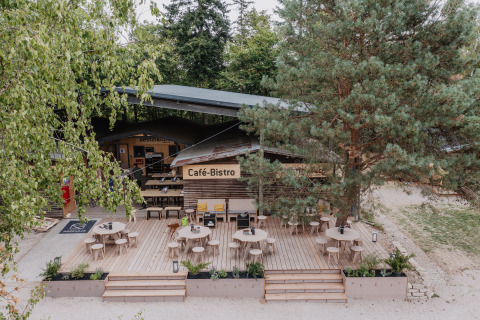 Terraza de Café-Bistro al aire libre en Chalet Destinature Südeifel, rodeada de naturaleza y árboles en verano.