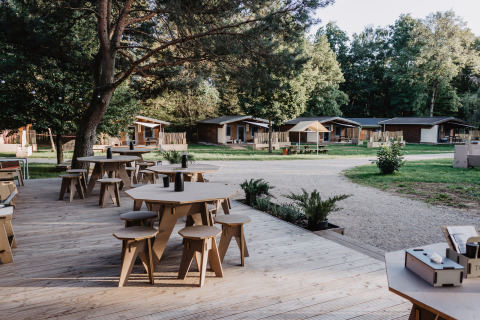 Outdoor deck with seating and tables in front of glamping cabins at Chalet Destinature Südeifel in the Eifel.