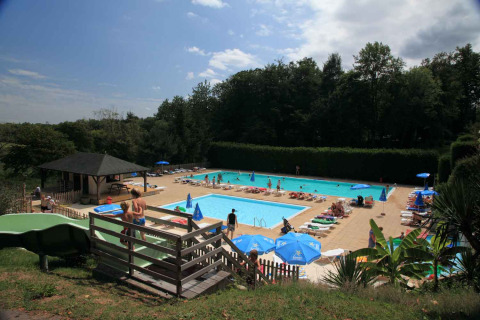 View of swimming pool area with sunbeds and guests at Vieflow Lodge - Lodgetenten Dordogne campsite.