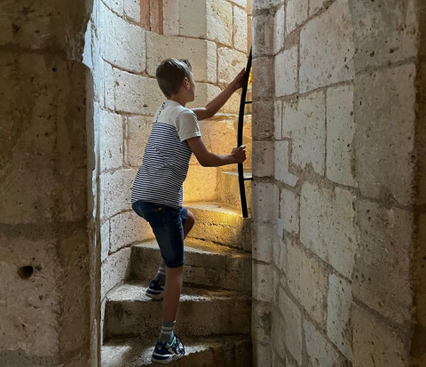 Niño subiendo una escalera de piedra en Vieflow Lodge - Lodgetenten Dordorgne glamping en plena luz.
