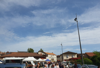 Mercado en Vieflow Lodge - Lodgetenten Dordorgne, personas recorriendo puestos bajo el cielo soleado.