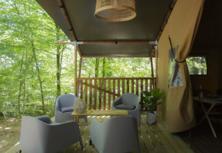 Udendørs terrasse ved Vieflow Lodge - Lodgetenten Dordorgne med moderne stole omgivet af frodig skov.