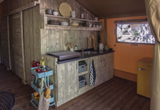 Glampingkeuken bij Vieflow Lodge Lodgetenten Dordorgne met houten kasten, open rekken en gele frigo.