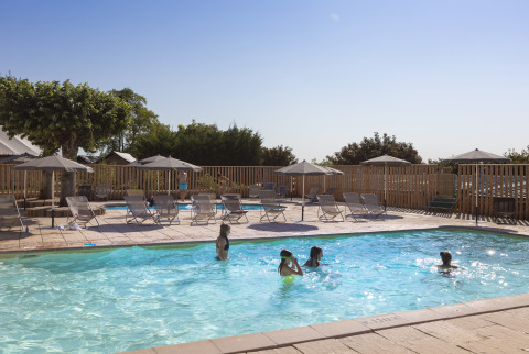 Udendørs poolområde med solsenge og parasoller på Huttopia Meursault - Glamping Bourgogne på en solrig dag.