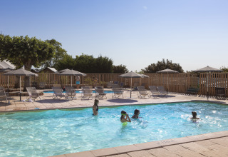 Piscina exterior con tumbonas y sombrillas en Huttopia Meursault - Glamping Bourgogne en un día soleado.