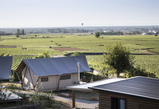 Alojamiento glamping en Huttopia Meursault con tiendas de lujo y vistas a los viñedos soleados de Borgoña.
