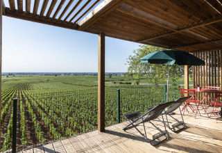 Terrasse avec transats et parasol surplombant les vignes à Huttopia Meursault - Glamping Bourgogne.