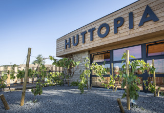 Entrada de Huttopia Meursault - Glamping Bourgogne con fachada de madera moderna y vides en primer plano