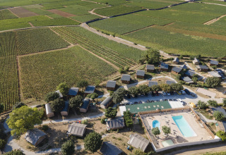 Luftfoto af Huttopia Meursault glampingplads med telte og swimmingpool, omgivet af vinmarker i Bourgogne.