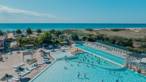 Amplia zona de piscina al aire libre con glamping, tumbonas y vista al mar en Camping Beach Garden Sur de Francia.