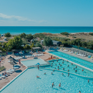 Ampia area piscina all'aperto con glamping, lettini e vista mare presso Camping Beach Garden nel sud della Francia.