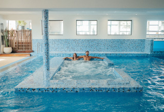 Espace piscine intérieure avec deux personnes détendues dans un jacuzzi au Camping Beach Garden - Glamping Sud de la France.
