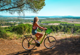 Femme à vélo près du Camping Beach Garden - Glamping Zuid-Frankrijk, admirant la vue sur la campagne.