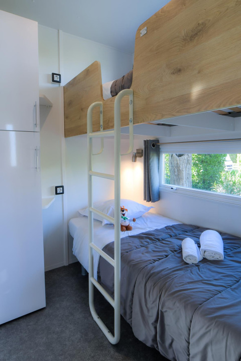 Interior of a glamping mobile home at Camping Beach Garden with bunk beds, window, and modern decor.