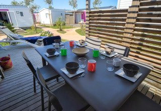 Gedekte eettafel op houten terras, glampingaccommodaties op de achtergrond bij Camping Beach Garden, Zuid-Frankrijk.