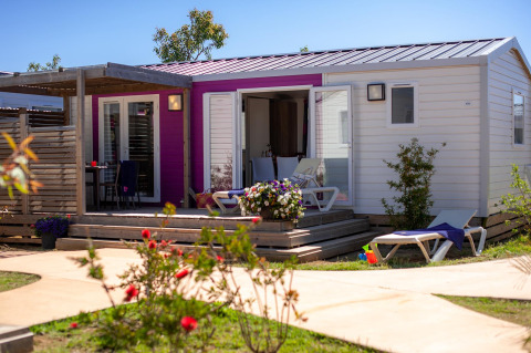 Alojamiento glamping en Camping Beach Garden, Sur de Francia, con terraza soleada y plantas floridas.