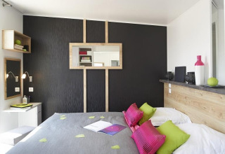 Modern glamping interior at Camping Beach Garden, South of France, featuring colorful pillows and stylish décor.