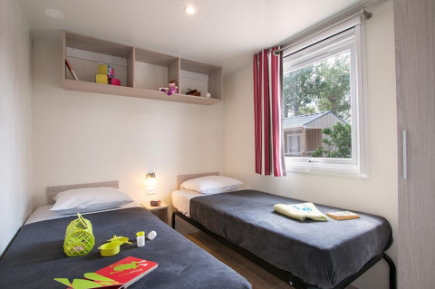 Binnenaanzicht van een gezellige glampingkamer met twee eenpersoonsbedden op Camping Beach Garden, Zuid-Frankrijk.