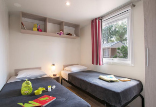 Indvendigt billede af et komfortabelt glampingværelse på Camping Beach Garden i Sydfrankrig med to enkeltsenge.