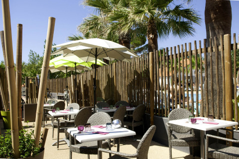 Espace repas extérieur avec parasols et chaises en osier au Camping Beach Garden - Glamping Sud de la France.