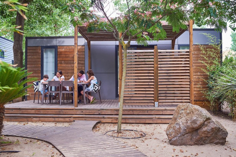 Familie entspannt sich auf der Terrasse einer modernen Glamping-Unterkunft im Beach Garden Camping Südfrankreich.