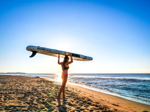 Donna con tavola da paddle sulla spiaggia al tramonto, Camping Beach Garden - Glamping Sud Francia