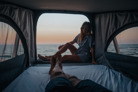 Zwei Menschen genießen den Sonnenuntergang am Meer vom komfortablen Glamping-Zelt bei Camping Beach Garden.