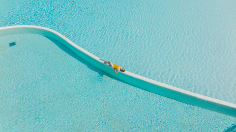 Persona relajándose en el borde de una piscina cristalina en Camping Beach Garden - Glamping Sur de Francia.