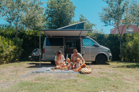 Familie beim Glamping auf dem Camping Beach Garden in Südfrankreich, entspannt vor ihrem Wohnmobil.