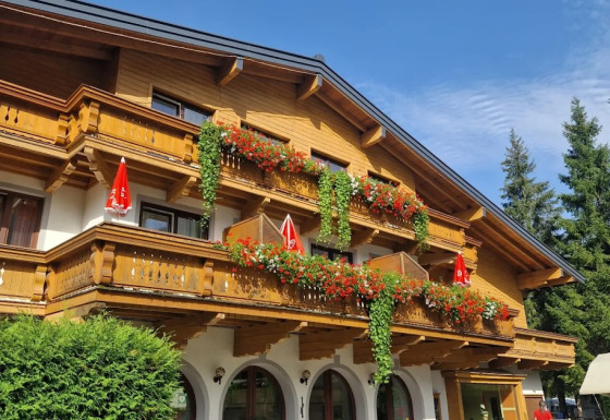 Chalet en bois à Glamping Bad Gastein - Kurcamping Erlengrund avec balcons fleuris et verdure.