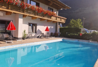 Buitenzwembad bij Glamping Bad Gastein - Kurcamping Erlengrund met uitzicht op bergen en bloemenbalkon.