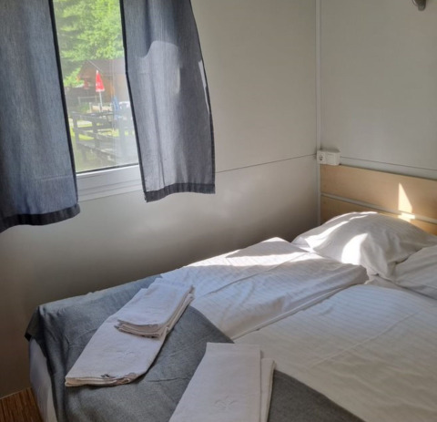 Camera con letto matrimoniale, asciugamani puliti e finestra, glamping al Glamping Bad Gastein - Kurcamping Erlengrund.