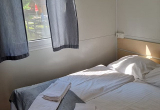 Habitación con cama doble, toallas limpias y ventana, alojamiento en Glamping Bad Gastein - Kurcamping Erlengrund.