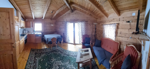 Cozy wooden cabin with exposed beams, kitchen, dining area, and lounge at Glamping Bad Gastein, Austria.
