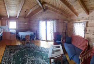 Gemütliche Holzhütte mit sichtbaren Balken, Küche, Essbereich und Wohnzimmer bei Glamping Bad Gastein.
