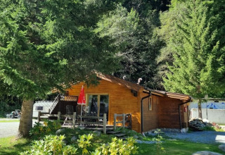 Cabaña de madera en Glamping Bad Gastein - Kurcamping Erlengrund rodeada de árboles y paisajes verdes.