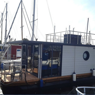 Husbåd Wind & Wellen - Woontboot Sleeswijk-Holstein fortøjet på en marina, perfekt til glampingophold.