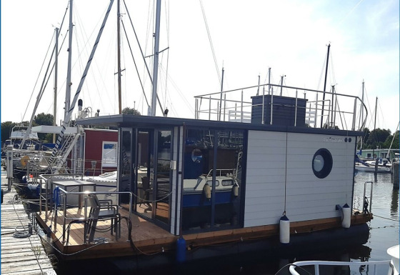 Husbåd Wind & Wellen - Woontboot Sleeswijk-Holstein fortøjet på en marina, perfekt til glampingophold.