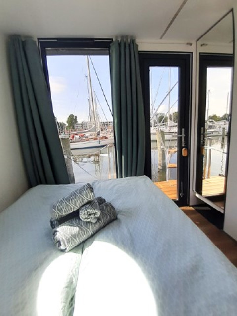 Dormitorio en Wind & Wellen Woontboot Sleeswijk-Holstein con vista a la marina y veleros amarrados.