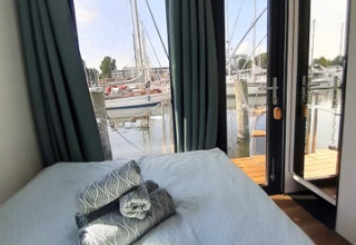 Dormitorio en Wind & Wellen Woontboot Sleeswijk-Holstein con vista a la marina y veleros amarrados.