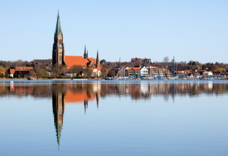View of the town with church tower, boats, and water reflection in Schleswig, seen from Wind & Wellen - Woontboot Schleswig-Holstein.