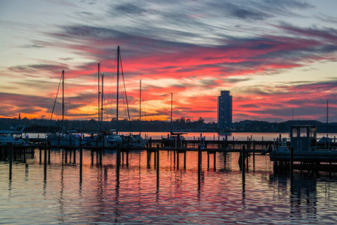 Zonsondergang bij de jachthaven van Wind & Wellen - Woontboot Sleeswijk-Holstein met boten en toren.