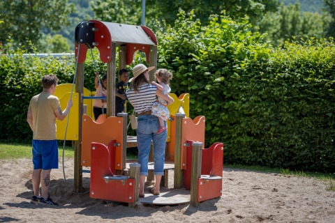 Børn og voksne leger på legepladsen ved Camping Gülser Moselbogen - Herderwagens Rijnland-Palts.