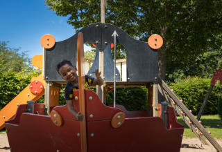 Un bambino gioca su un parco giochi a forma di nave al Camping Gülser Moselbogen - Herderwagens Renania-Palatinato.