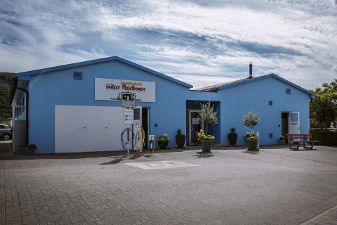 Blåt bygning ved Camping Gülser Moselbogen med servicefaciliteter og grønne planter, Rhinlandet-Pfalz