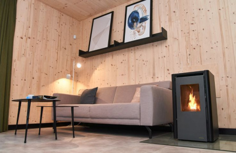 Modernes Wohnzimmer im UplandParcs Sauerland Wellness Cottage mit Sofa, Holzofen und stilvoller Einrichtung.