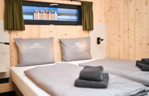 Hébergement glamping moderne à UplandParcs Sauerland Wellness Cottage avec lits jumeaux et murs en bois.