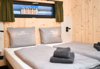Moderne glampingaccommodatie bij UplandParcs Sauerland Wellness Cottage met houten muren en tweepersoonsbed.