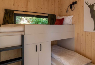 Et hyggeligt soveområde med køjesenge i træbeklædt værelse på UplandParcs Sauerland Wellness Cottage.