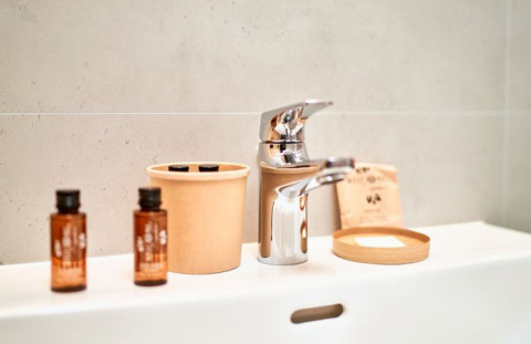 Badeværelsesdetaljer med håndvask, sæbedispenser, glas og toiletartikler på UplandParcs Sauerland Wellness Cottage.